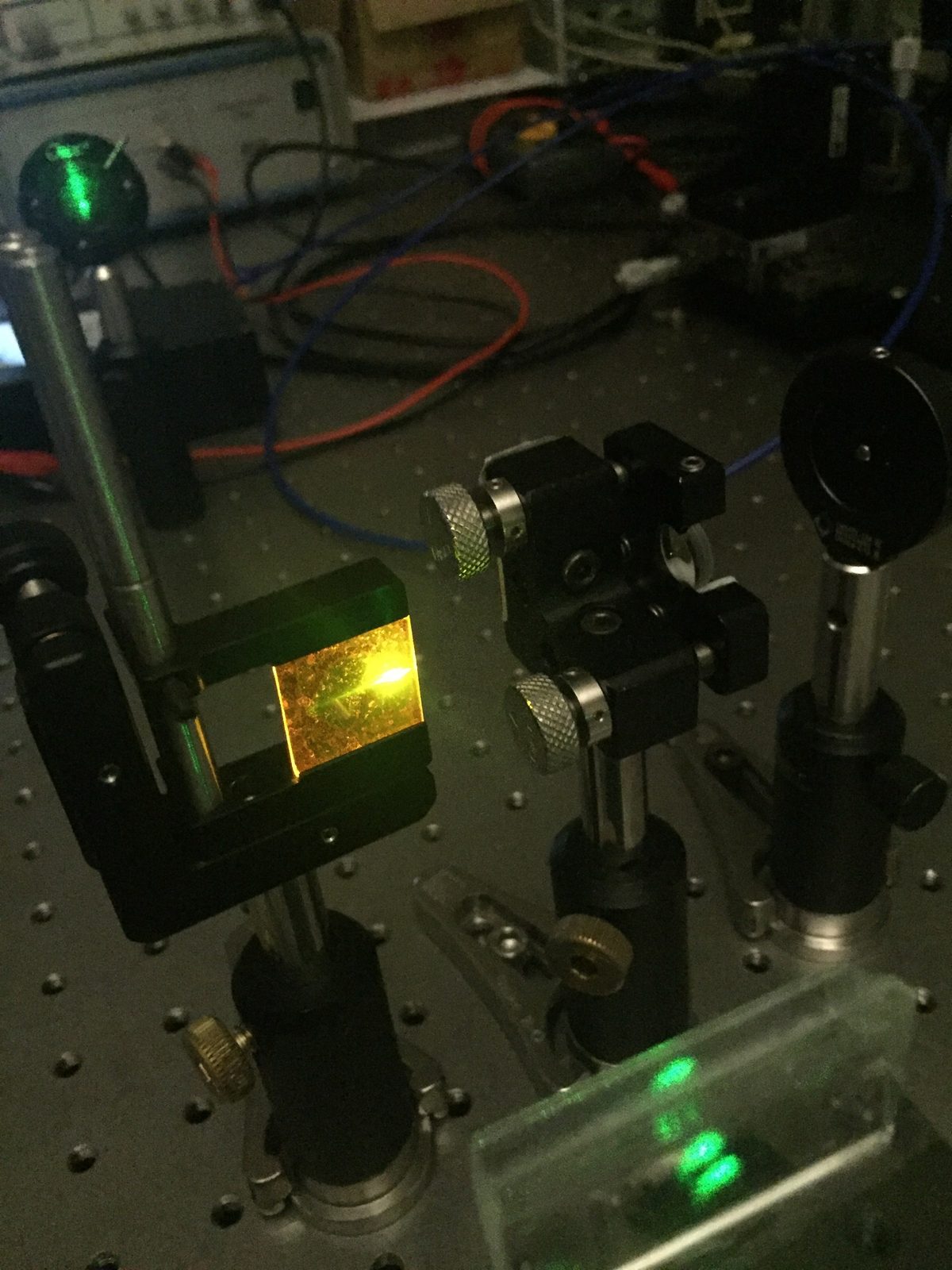 Optical bench with mirrors, lenses and a green laser beam