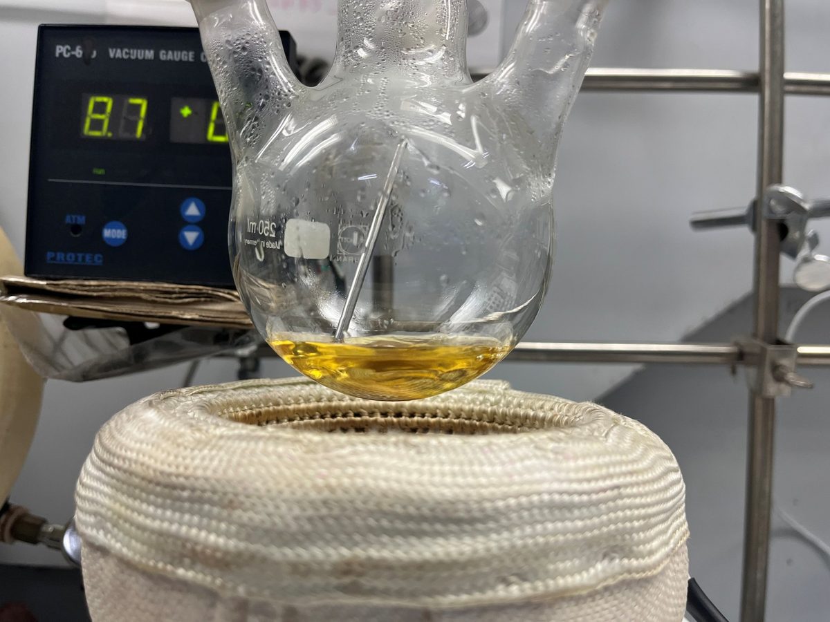 Round-bottom flask holding a golden reaction mixture on a heating mantle